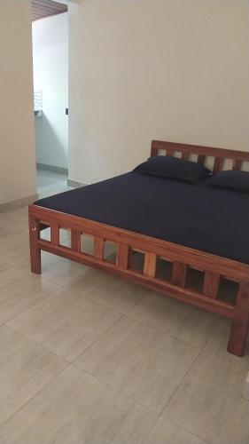 ein Bett mit einem Holzrahmen in einem Schlafzimmer in der Unterkunft Hotel white house mahiyanganaya in Mahiyangana