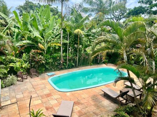 a swimming pool in a garden with palm trees at Ayo Bistrô Pousada in Marau