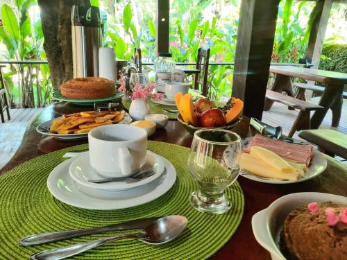 a table with plates of food and a cup of coffee at Ayo Bistrô Pousada in Marau