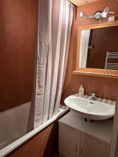 ein Badezimmer mit einem Waschbecken, einer Badewanne und einem Spiegel in der Unterkunft Charmant studio Risoul 1850 in Risoul