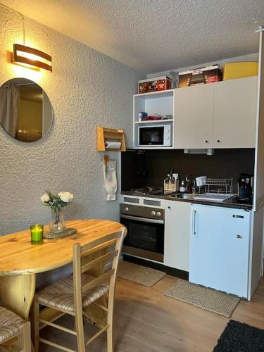 une cuisine avec une table en bois et une cuisine avec une table et une table dans l'établissement Charmant studio Risoul 1850, à Risoul