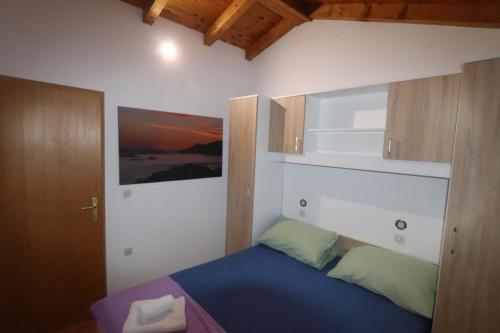 - une chambre avec un lit bleu et des placards en bois dans l'établissement Robin Borje, à Orebić