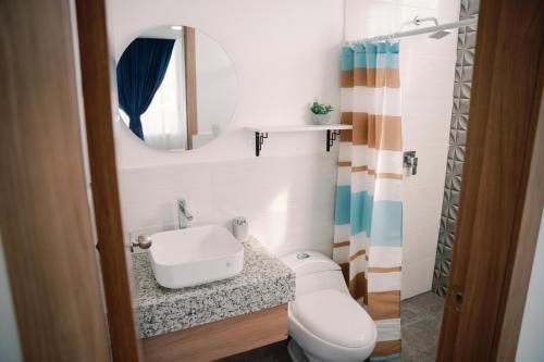a bathroom with a sink and a toilet and a mirror at Modernas Habitaciones in Puerto Ayora