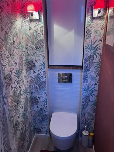 a bathroom with a white toilet and a wallpaper at Camera et Caetera Chambres d'hôtes B&B in Roubaix