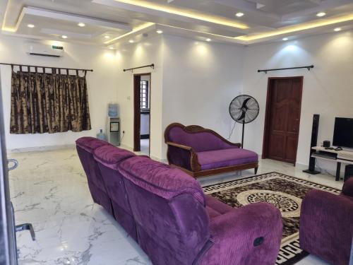 uma sala de estar com sofás roxos e uma televisão em AJALA Lodge em Badagry