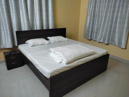 uma cama com lençóis brancos e almofadas num quarto em Mahadev Retreat em Faizābād