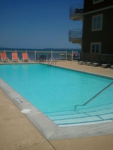 a large swimming pool with chairs and a building at Beautiful First Floor suite with patio to the Bay in Traverse City