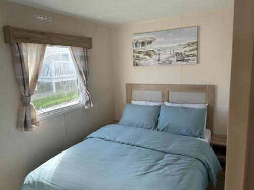 a bedroom with a bed with blue sheets and a window at The Lay By in Prestonpans
