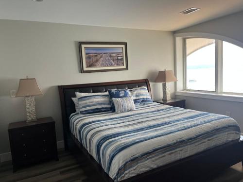 a bedroom with a bed with a striped comforter and two lamps at Beautiful views from Fifth Floor Suite in Traverse City