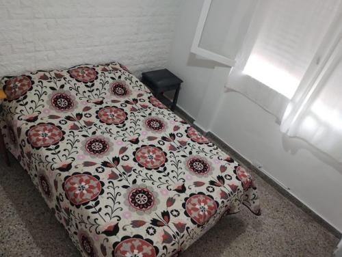 Cama en habitación con colcha floral en Almirante Brown 49, en Mar de Ajó