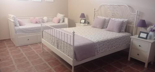 two beds in a bedroom with pink and white at Pandora Casa Rural en Madrigueras in Albacete