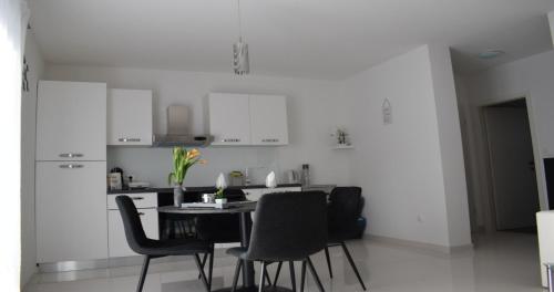 a kitchen with white cabinets and a table and chairs at Apartmani Foresta in Kras
