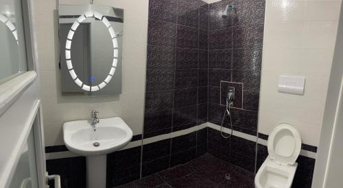 a bathroom with a sink and a toilet and a mirror at Diamond Hill Apartment in Vlorë