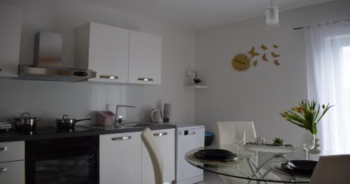 a kitchen with white cabinets and a glass table at Apartmani Foresta in Kras