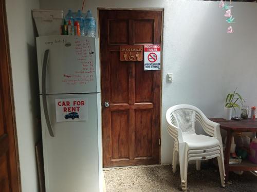 een keuken met een koelkast, een tafel en een stoel bij Hogar tico-estadounidense cerca de aeropuerto in Alajuela