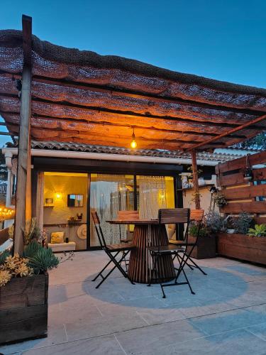 un patio avec une table et des chaises sous une pergola dans l'établissement Appartement à Pramousquier Le Lavandou, au Lavandou