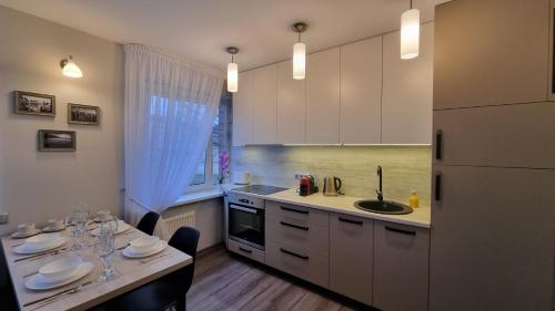 een keuken met witte kasten, een wastafel en een tafel bij Barona apartement in Jelgava