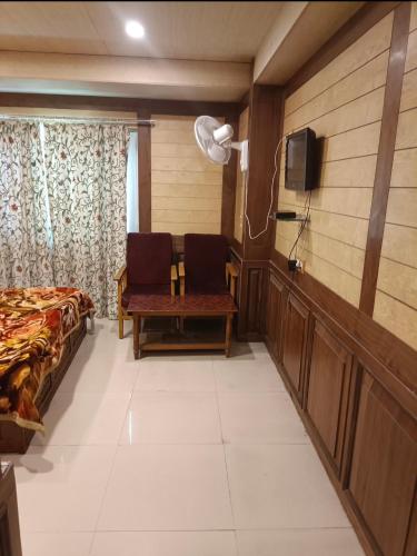 een kamer met een bed en twee stoelen en een televisie bij Royal stay in Srinagar