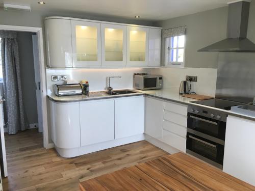 a kitchen with white cabinets and a sink at Portmeirion Village & Castell Deudraeth in Porthmadog