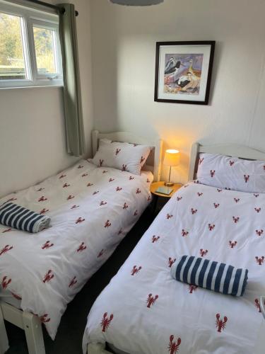 a bedroom with two beds and a window at Chalet 77, Kings Chalet park,Cromer,North Norfolk. in Cromer
