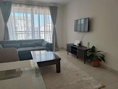 a living room with a blue couch and a tv at Eden Homes - NEAR JKIA & SGR in Nairobi