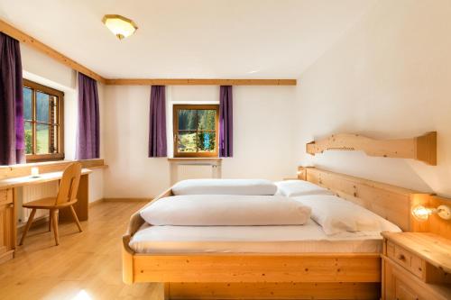 a bedroom with two beds and a desk and windows at Ferienhaus Daniel in Racines