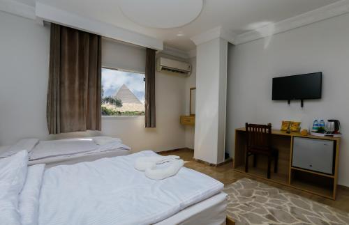 Pyramids Paradise View Inn Hotel في القاهرة: غرفة بسريرين ومكتب وتلفزيون