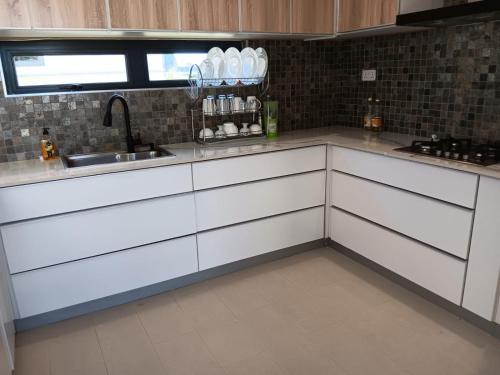 a kitchen with white cabinets and a sink at Palms Haven - Mauritius - Modern and luxury vacation home in Phoenix