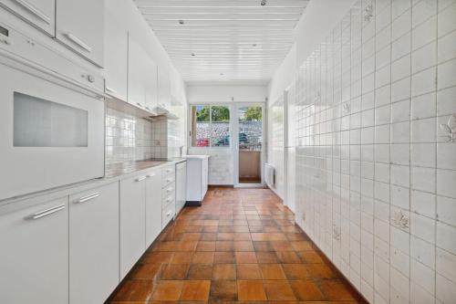 une cuisine avec des placards blancs et un couloir carrelé dans l'établissement Escapade à Monaco, appartement vue mer et plage, à Saint-Antoine