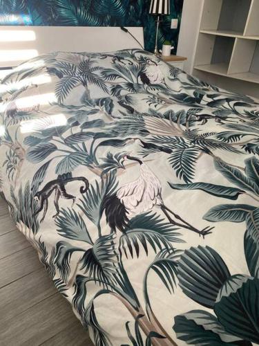 un lit avec une couette noire et blanche avec des plantes dans l'établissement Agréable logement 2 chambres, à Saint-Saulve