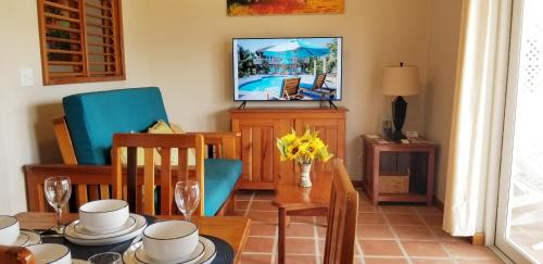 a dining room with a table and chairs and a television at Sapphire Beach Condo in San Pedro