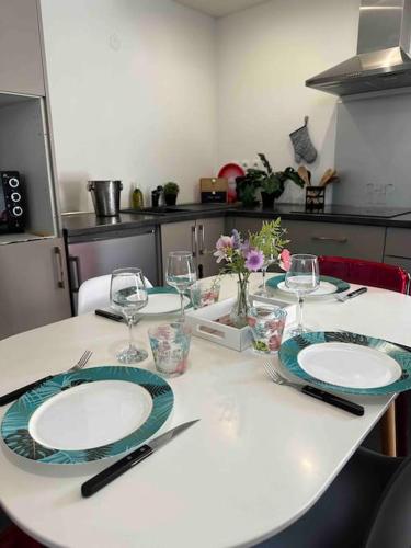 une table avec des assiettes et des verres à vin dessus dans l'établissement Agréable logement 2 chambres, à Saint-Saulve
