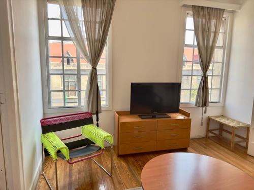 a living room with two green chairs and a television at Massiosare El Hostal in Mexico City