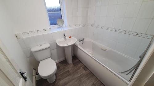 a white bathroom with a toilet and a sink at Lovely 3 Bedroom House in Greater Manchester in Manchester