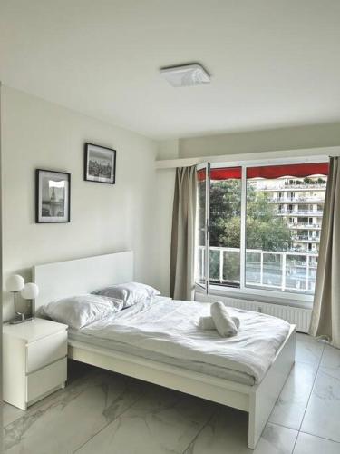 ein weißes Schlafzimmer mit einem Bett und einem Fenster in der Unterkunft Logement Woluwé in Brüssel