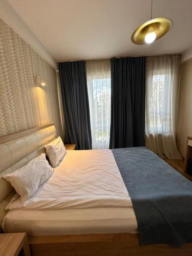 a bedroom with a large bed in front of windows at Hotel Lile in Tbilisi City
