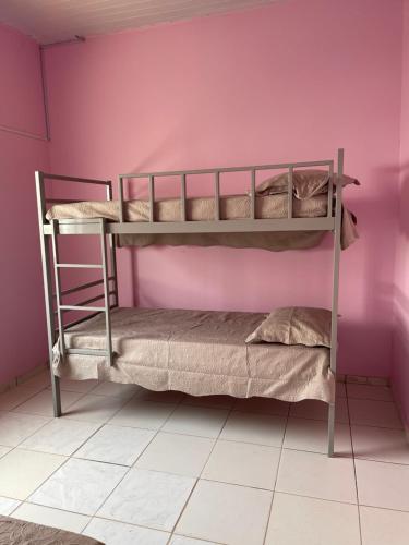 Ce lit se trouve dans un dortoir doté de 2 lits superposés et d'un mur rose. dans l'établissement Kit net CN, à Ananindeua