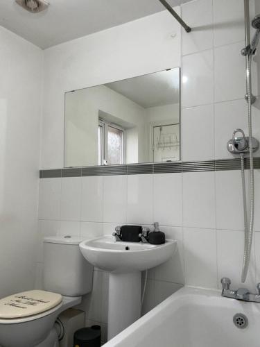 a bathroom with a sink and a toilet and a mirror at City Airport Apartment in Wythenshawe