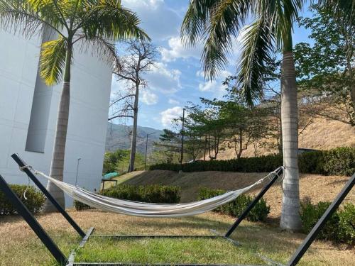 a hammock in front of a building with palm trees at Hermoso y acogedor apartamento! in Santa Fe de Antioquia
