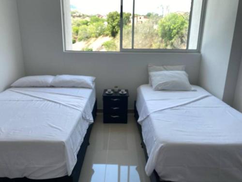 two beds in a small room with a window at Hermoso y acogedor apartamento! in Santa Fe de Antioquia