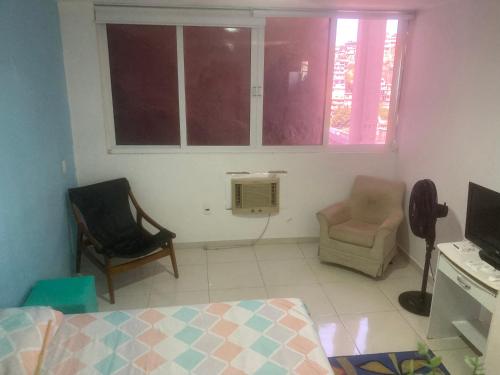 a bedroom with a bed and a chair and a window at Vidigal Sol in Rio de Janeiro