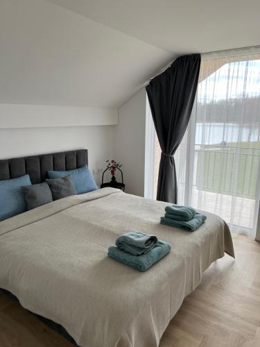 a bedroom with a large bed with two towels on it at Panacea in Lazdijai