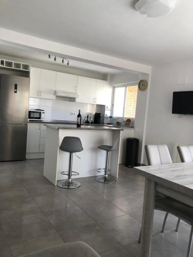 a kitchen with white cabinets and a table with stools at Casa de Feliz in Calpe