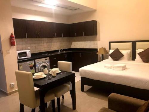 een kamer met een bed en een tafel en een bed en een keuken bij Luxury Studio/Apartment in JVC in Dubai