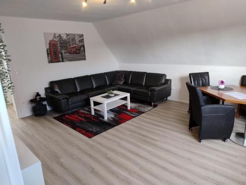 a living room with a black leather couch and a table at LaPurka ll Home in Nordhorn
