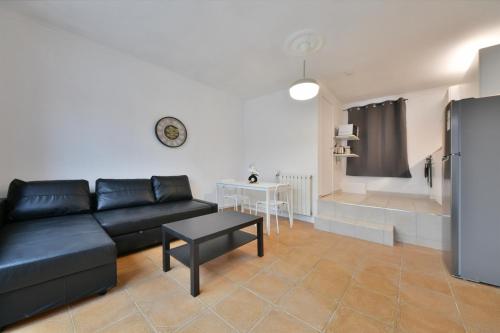 un salon avec un canapé noir et une table dans l'établissement Confortable appartment near Stade de France, à Saint-Denis