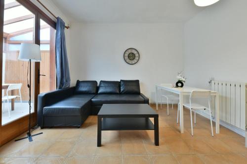 un salon avec un canapé noir et une table dans l'établissement Confortable appartment near Stade de France, à Saint-Denis