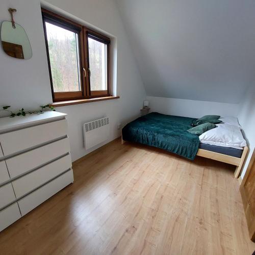 a bedroom with a bed and a dresser and a window at Na Kamieńcu domki in Rzyki