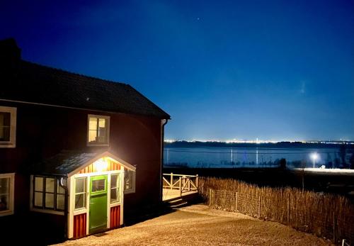a house with a brightly lit window and a body of water at Flemma Gård The lake view with sauna in Vreta Kloster