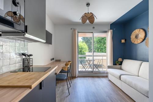 Il comprend une cuisine et un salon avec des murs bleus et un canapé. dans l'établissement Studio rénové avec balcon près des Champs-Elysées, à Paris